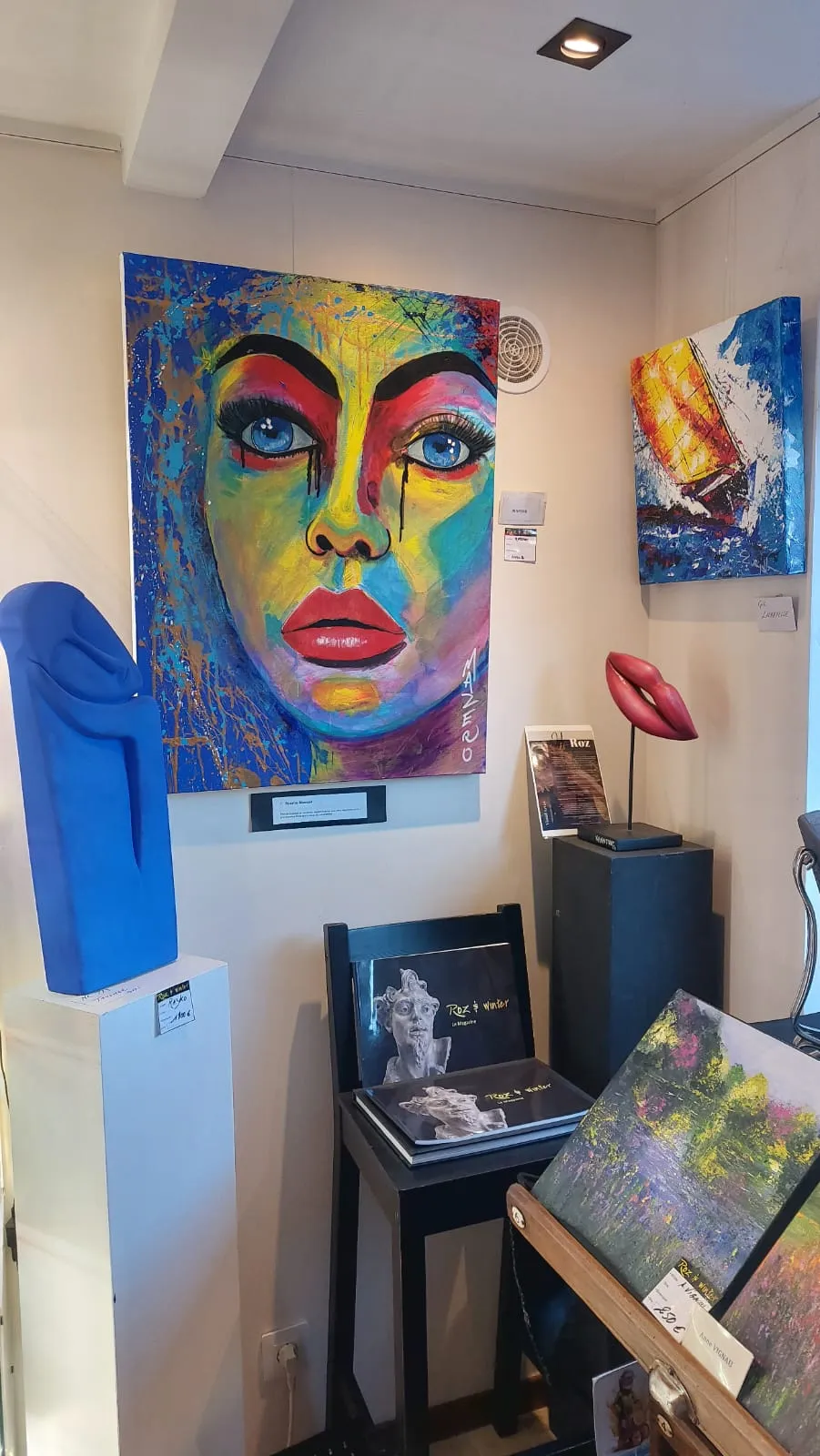 Coin contemporain de la galerie : grand portrait coloré, sculpture bleue et sculpture de lèvres rouges